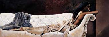 A beautiful and sophisticated Black woman lounges on a plush white sofa 